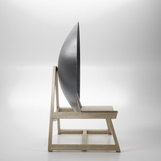 Rendering of a the profile view of wooden chair with a large parabolic disc behind the backrest